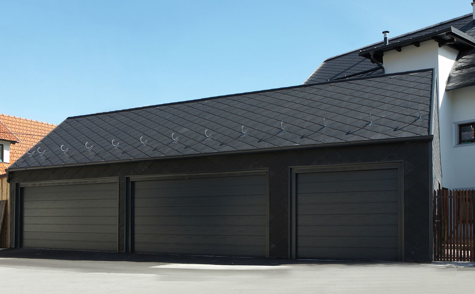 Garagenzubau mit Fassade und Dach aus dunkelgrauem Eternit.