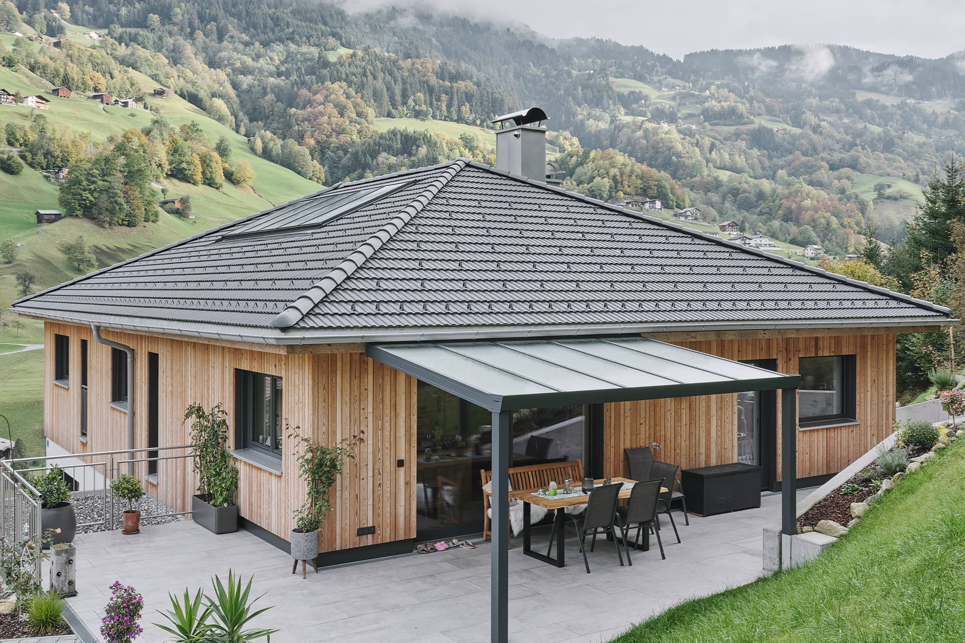 Das Bild zeigt ein modernes Haus mit grauem Walmdach der Marke Swisspearl.