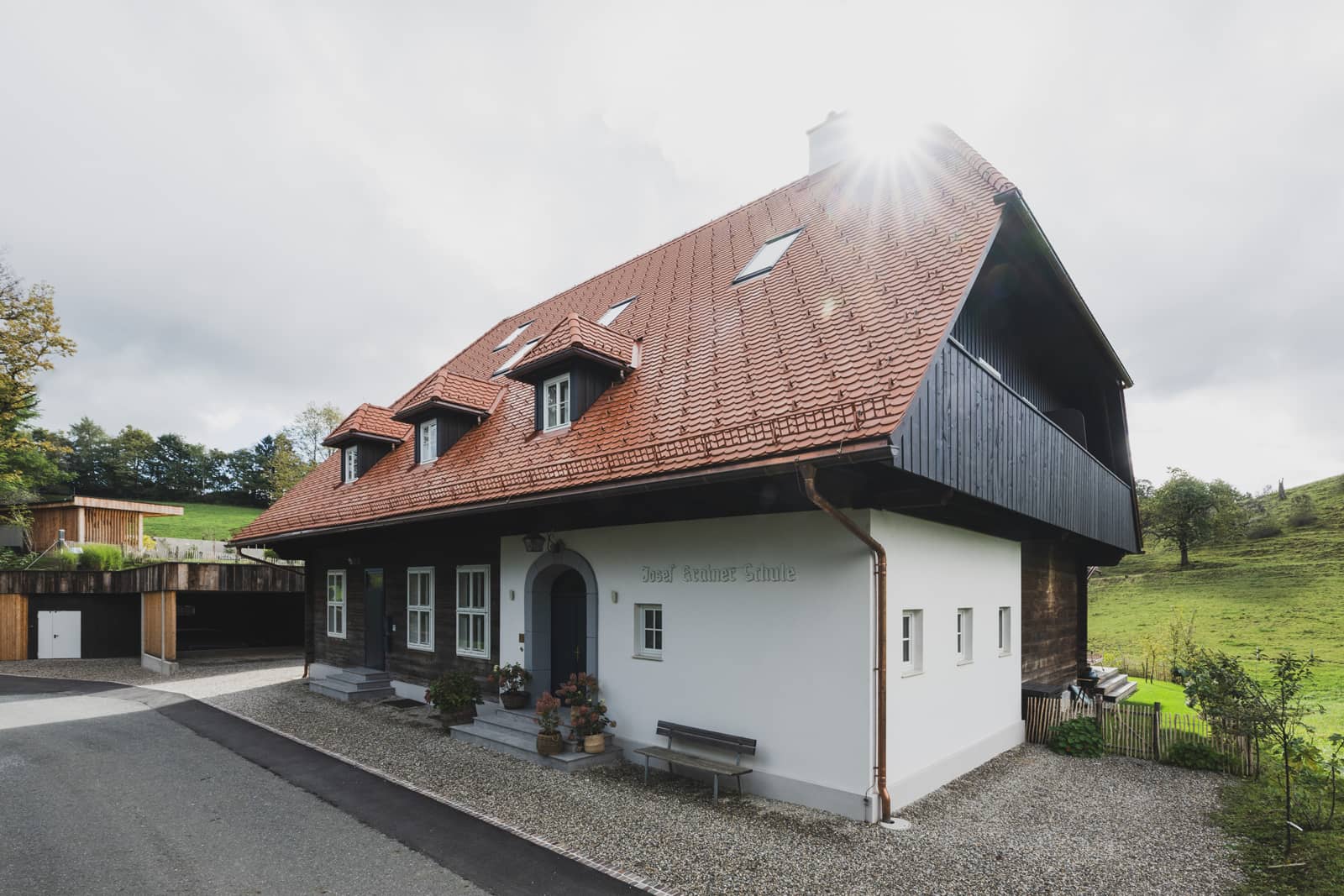 Das Bild zeigt ein renoviertes, älteres haus mit einem neuen, orangen Satteldach.
