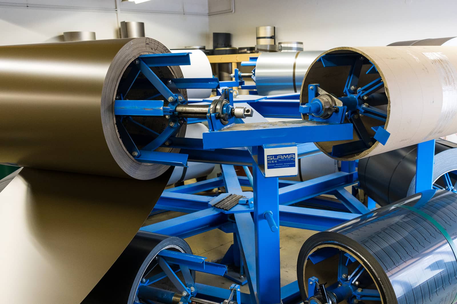 Das Bild zeigt eine Maschine, in der verschiedene Rollen mit Metall eingespannt sind, um die weiter zu verarbeiten.