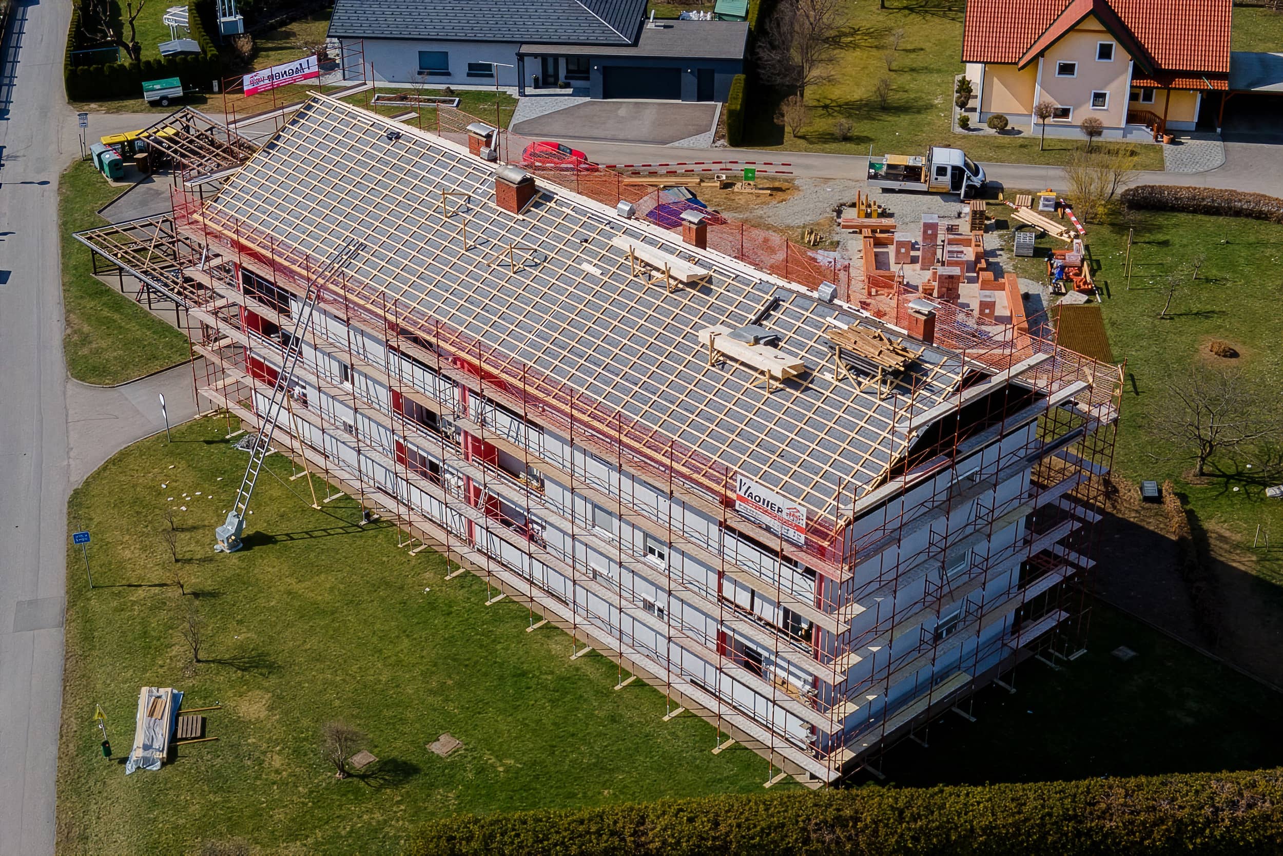 Das Bild aus der Vogelperspektive eine Dachbaustelle, wo gerade Arbeiten an der Unterkonstruktion im Gange sind.